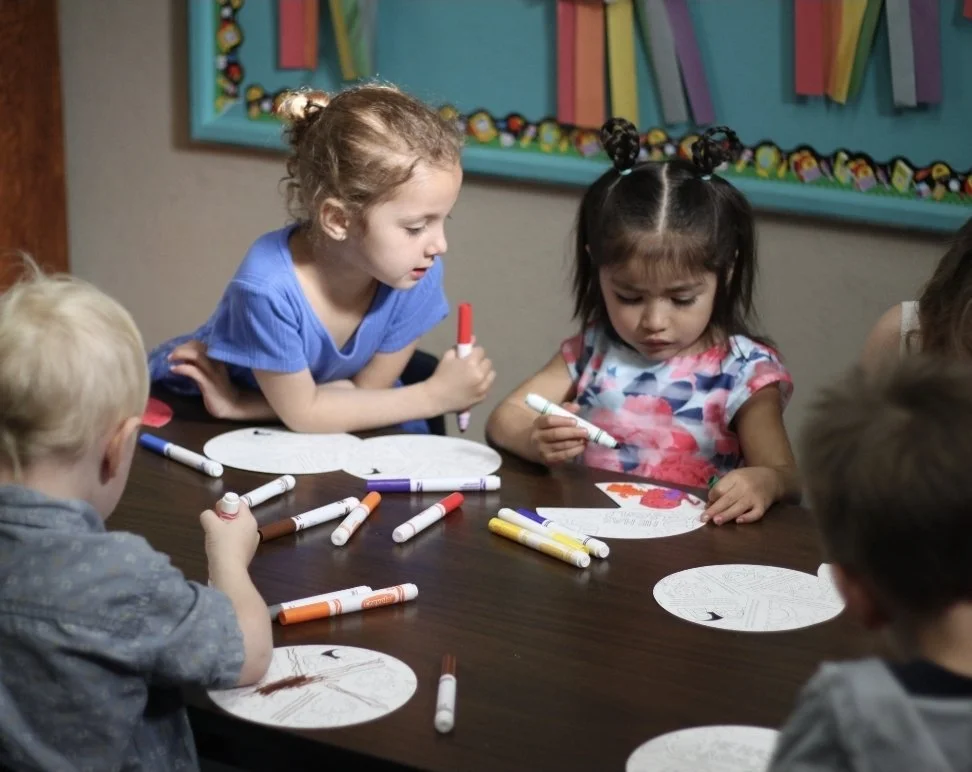 Children participating in arts and crafts activity at a table, using markers on paper Ohio.