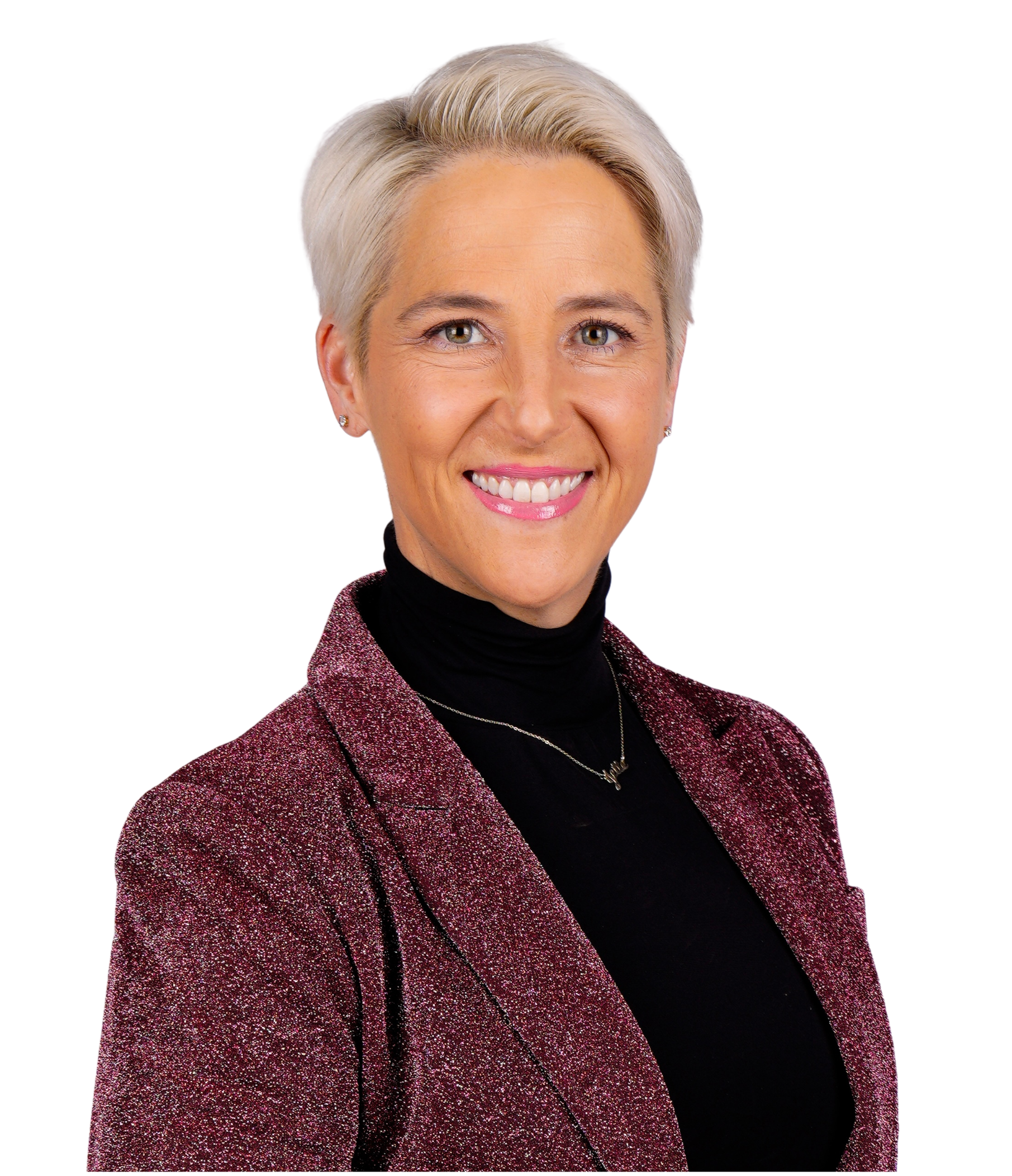 Brooke Weisbrod with short blonde hair, wearing a sparkly red blazer over a black turtleneck, smiling at the camera.