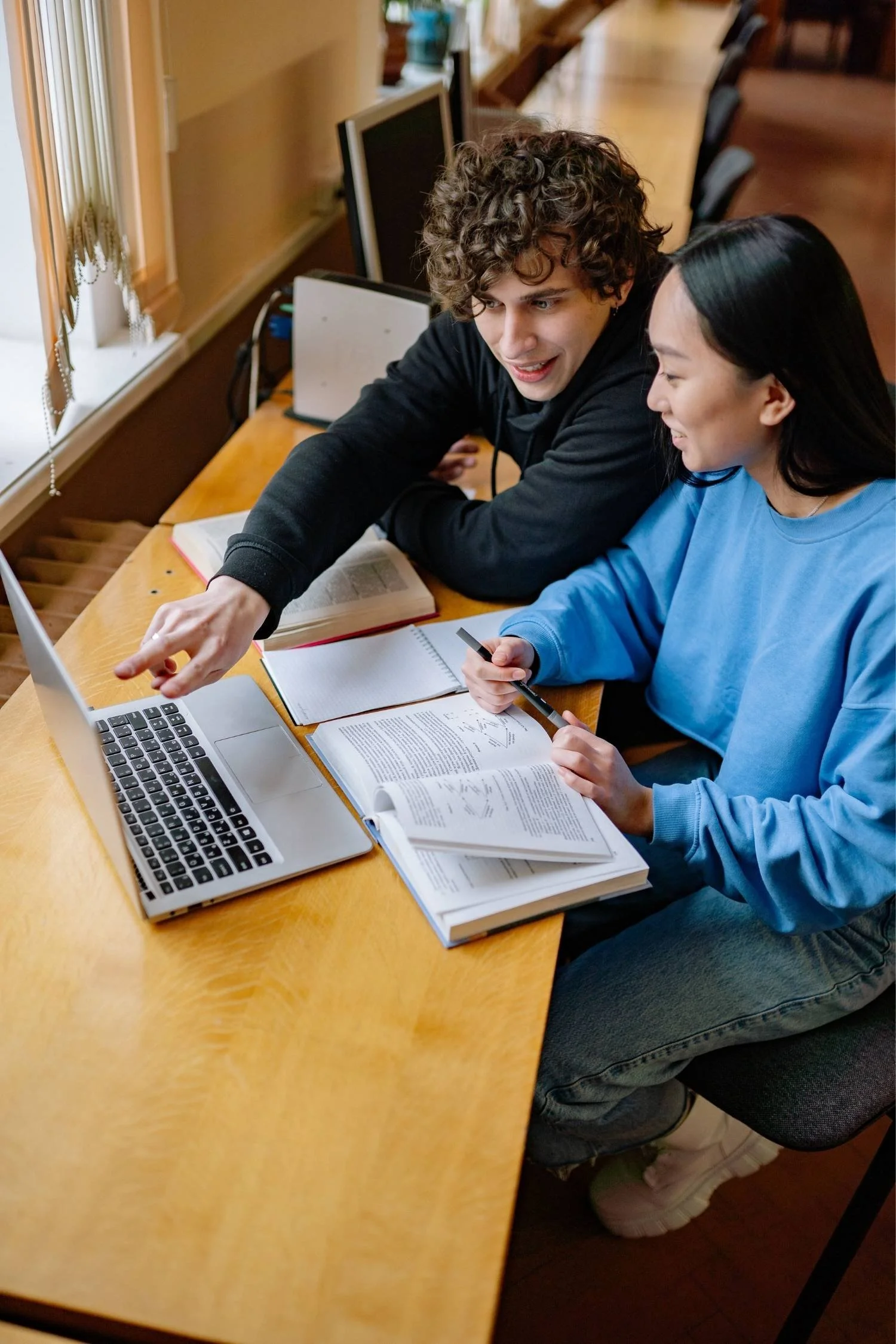 Two students collaborating on coursework with a laptop, representing student scholarships, Illinois education scholarships, and student excellence scholarship opportunities that support academic success.