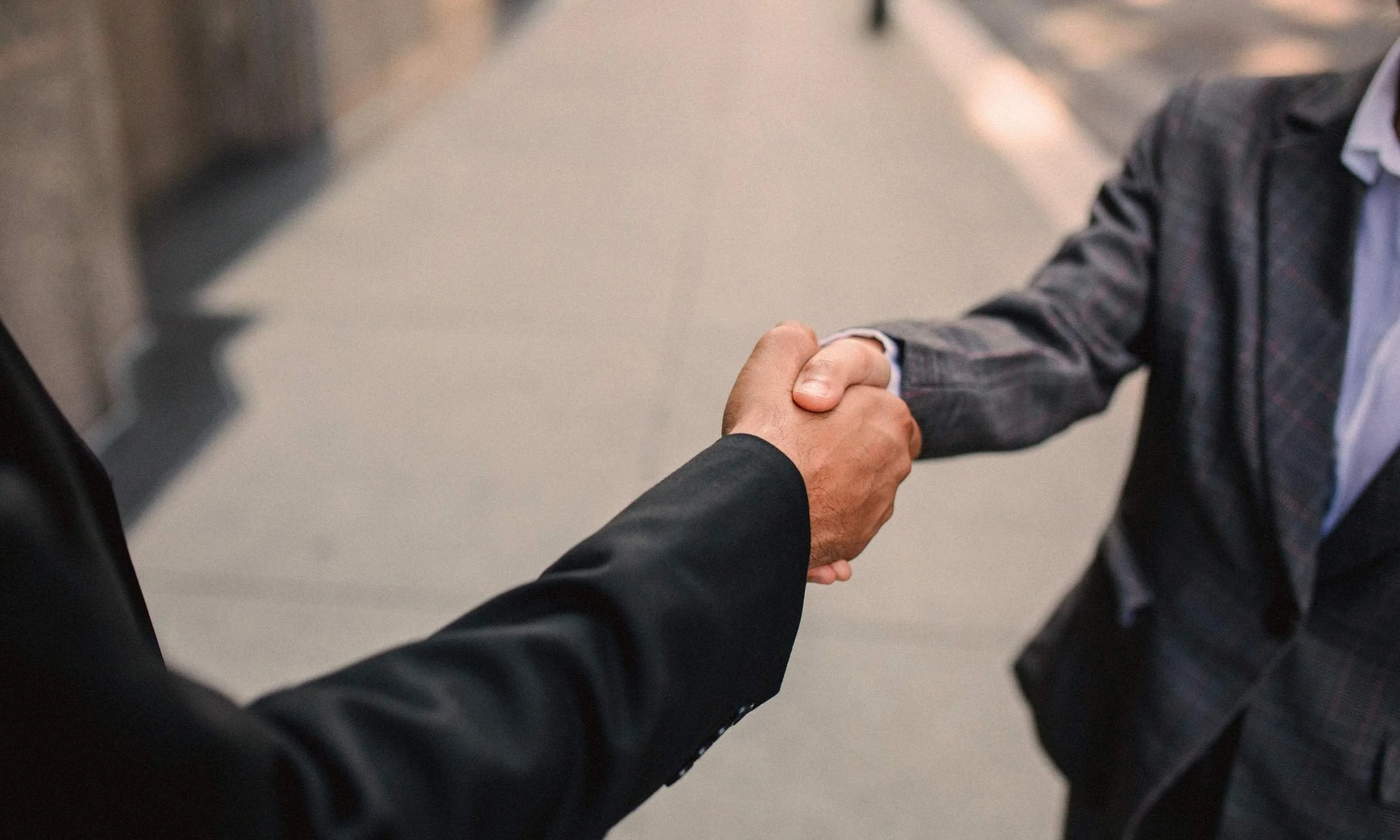 Two professionals shaking hands to celebrate a partnership supporting a 501(c)(3) nonprofit organization dedicated to scholarships, mentorship, and student success.