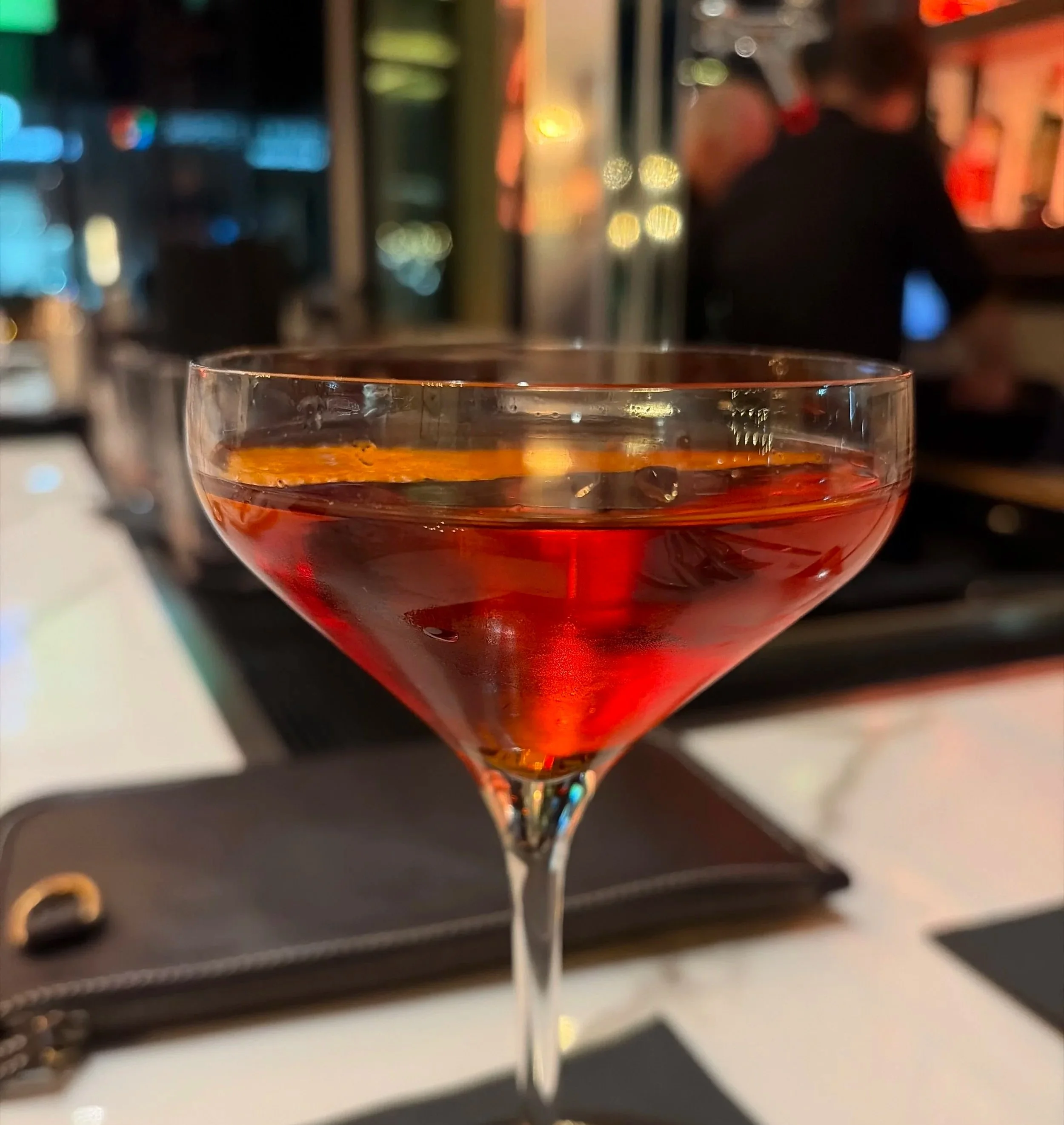 A Negroni on a table at night with warm Las Vegas restaurant lights in the background.