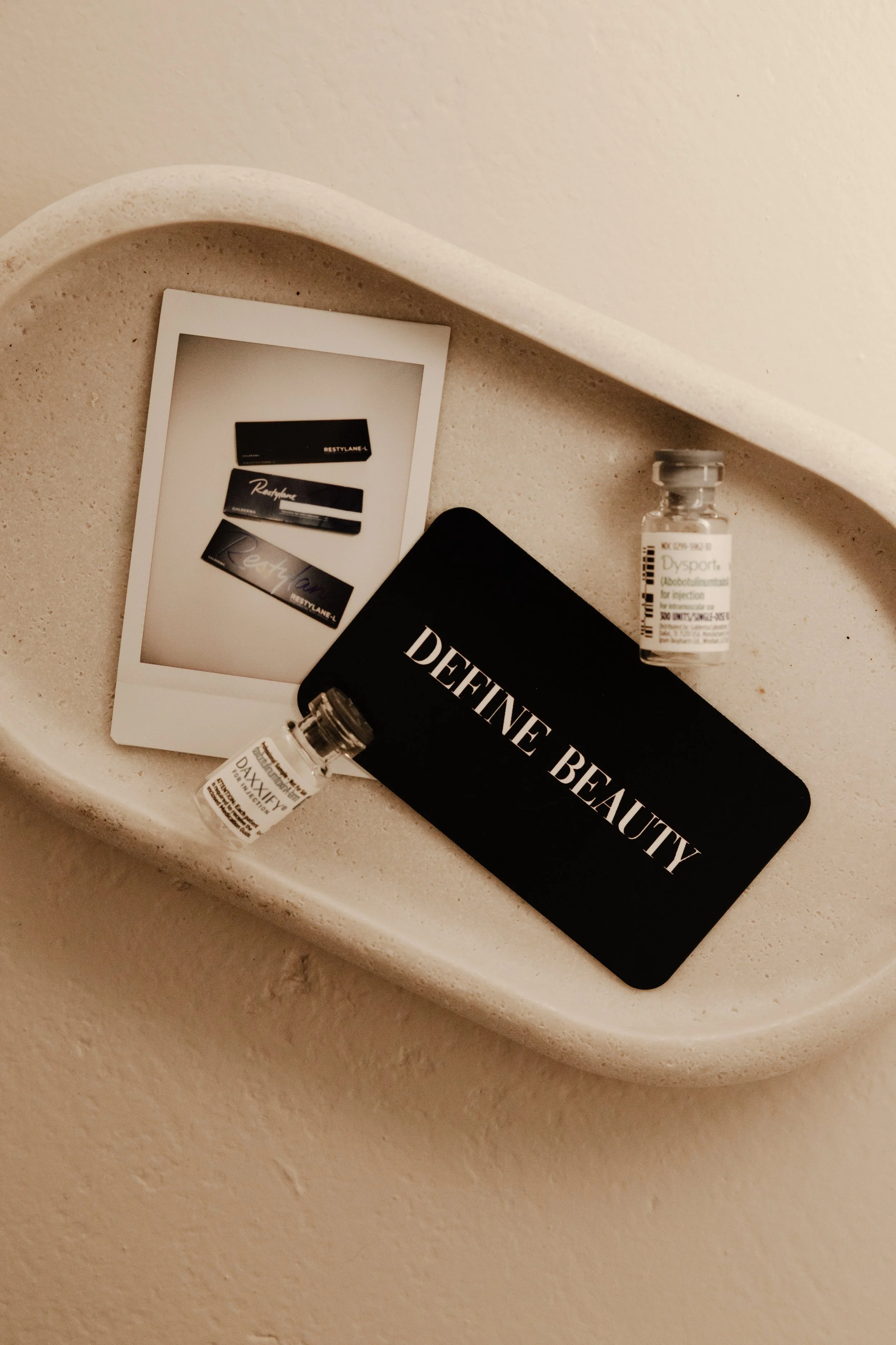 Medical vials and skincare products on a cream-colored surface.