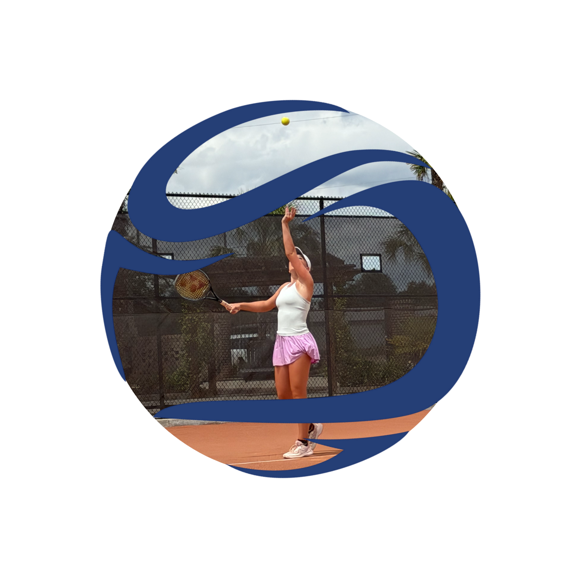 A female tennis player in a white tank top and pink skirt serving a tennis ball on an outdoor court with a chain-link fence and trees in the background.
