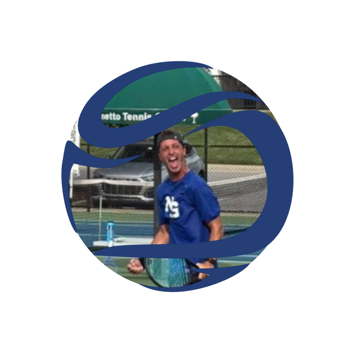 A tennis player celebrating on the court with his mouth open and fist clenched, wearing a blue shirt, holding a tennis racket, with a tennis court and fence in the background.
