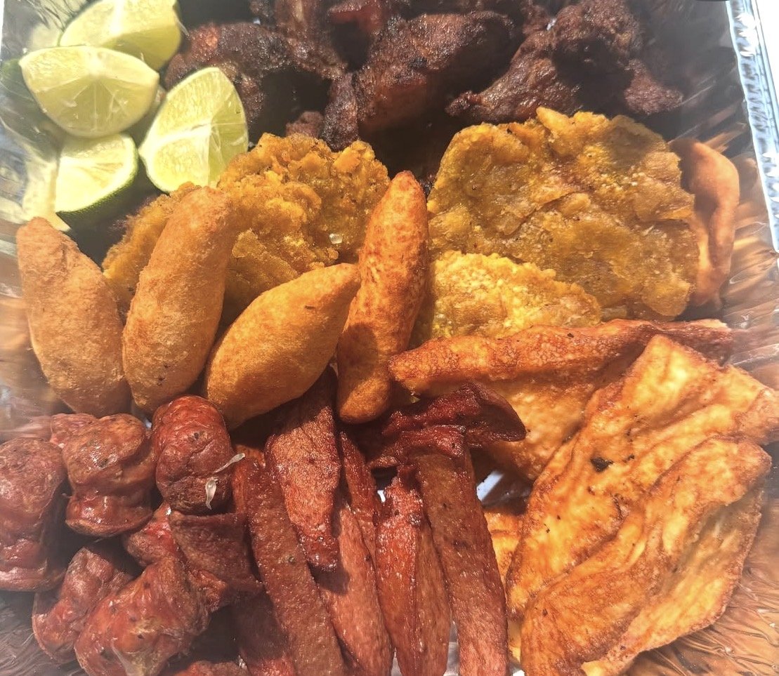 Selection of fried and grilled meats with lemon wedges in a serving tray.
