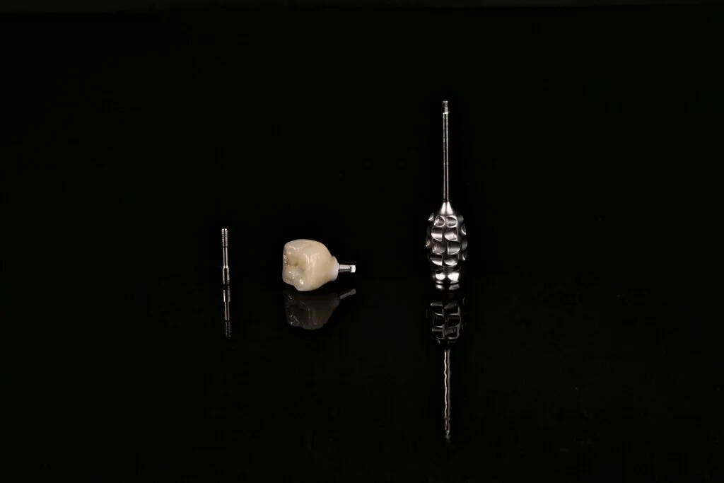 Dental drill bits and a tooth model on a black background.