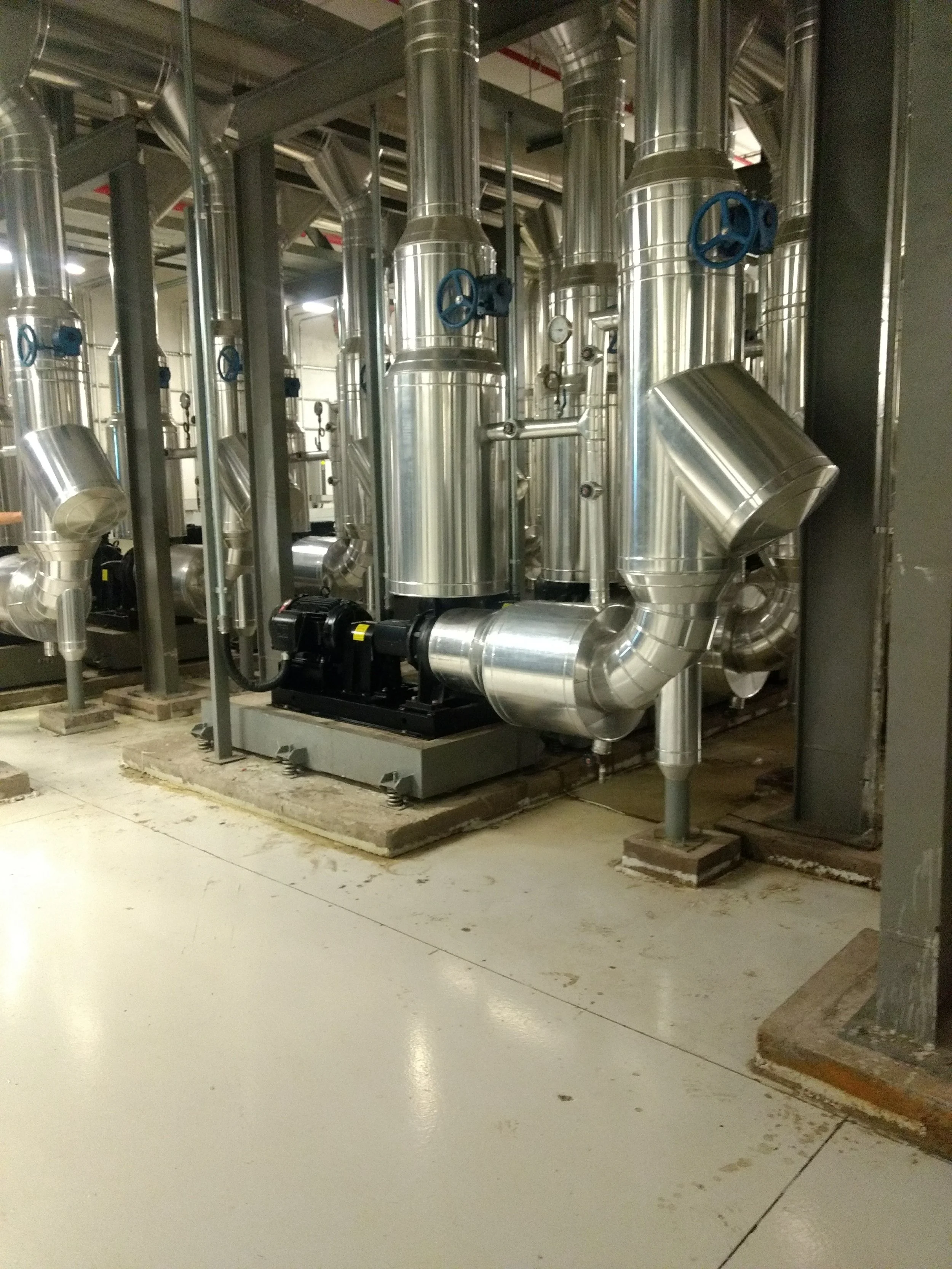 Sistema de tuberías de acero inoxidable en una planta industrial, con válvulas y medidores.