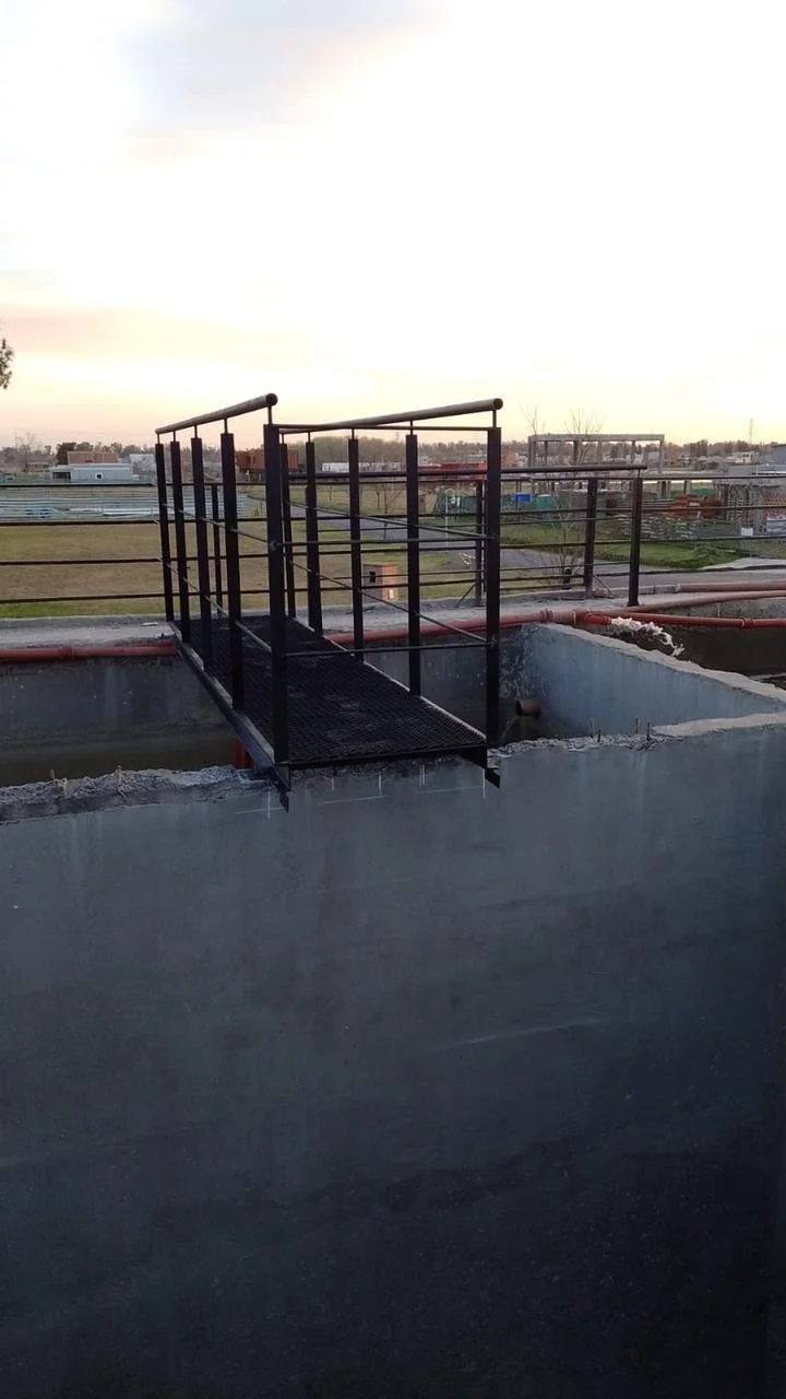 Pasarela de metal en la azotea de un edificio, con vista a un área urbana desde el horizonte.
