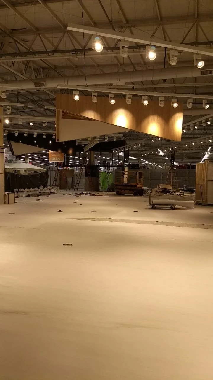 Interior de un supermercado en construcción o cierre, con suelo despejado, iluminación y estructuras en progreso.