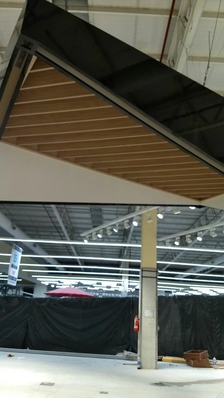 Interior de un espacio comercial en construcción o renovación, con estructuras metálicas, ductos y protección negra en algunas áreas.