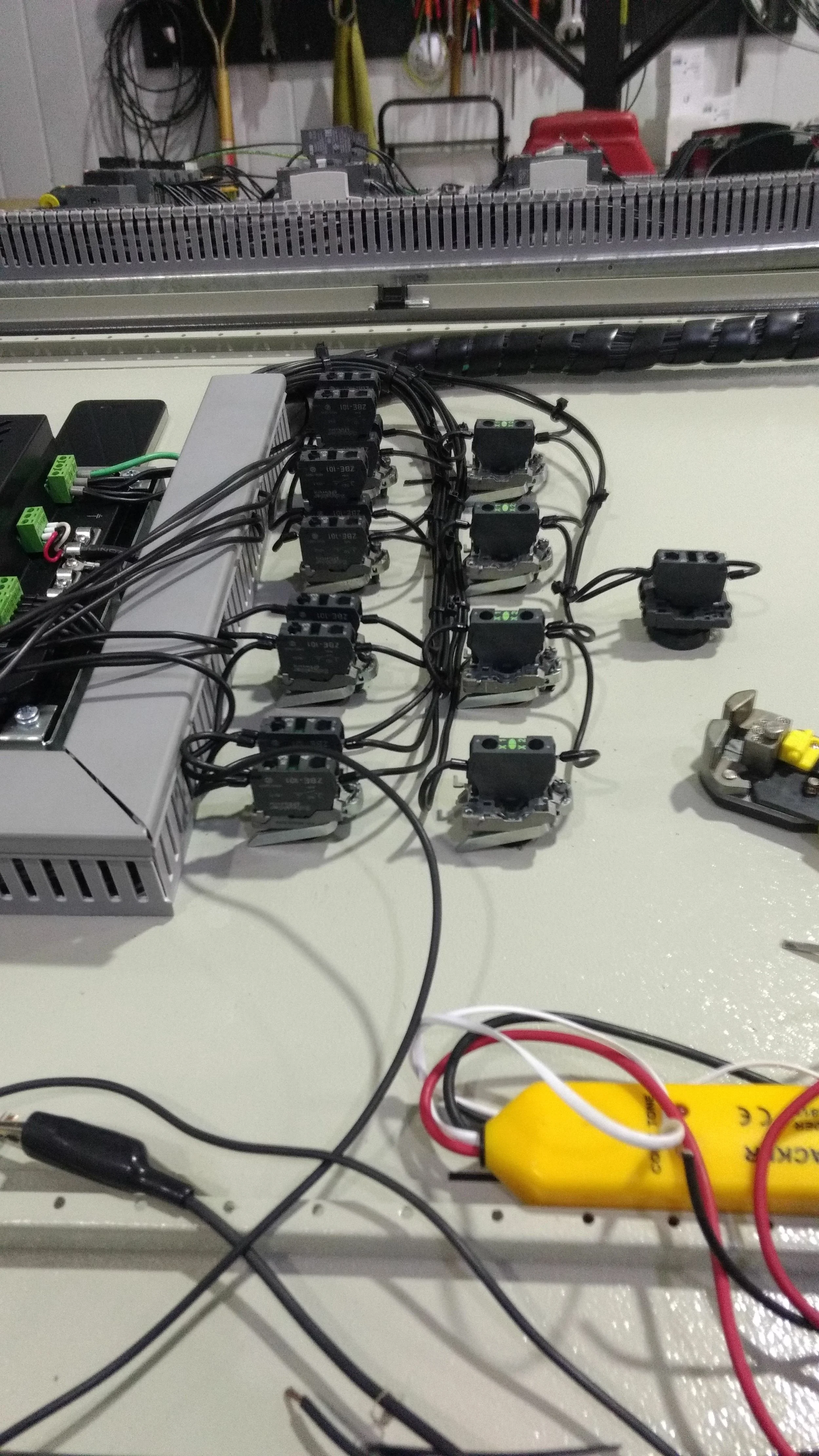Piso de trabajo con componentes electrónicos y cables conectados, incluyendo relés, una fuente de alimentación y otros dispositivos electrónicos en un taller técnico.