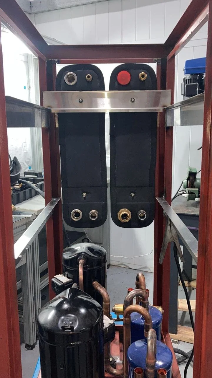 Componentes de un sistema de aire acondicionado, incluidos un compresor, filtros, y serpentines, montados en una estructura metálica.