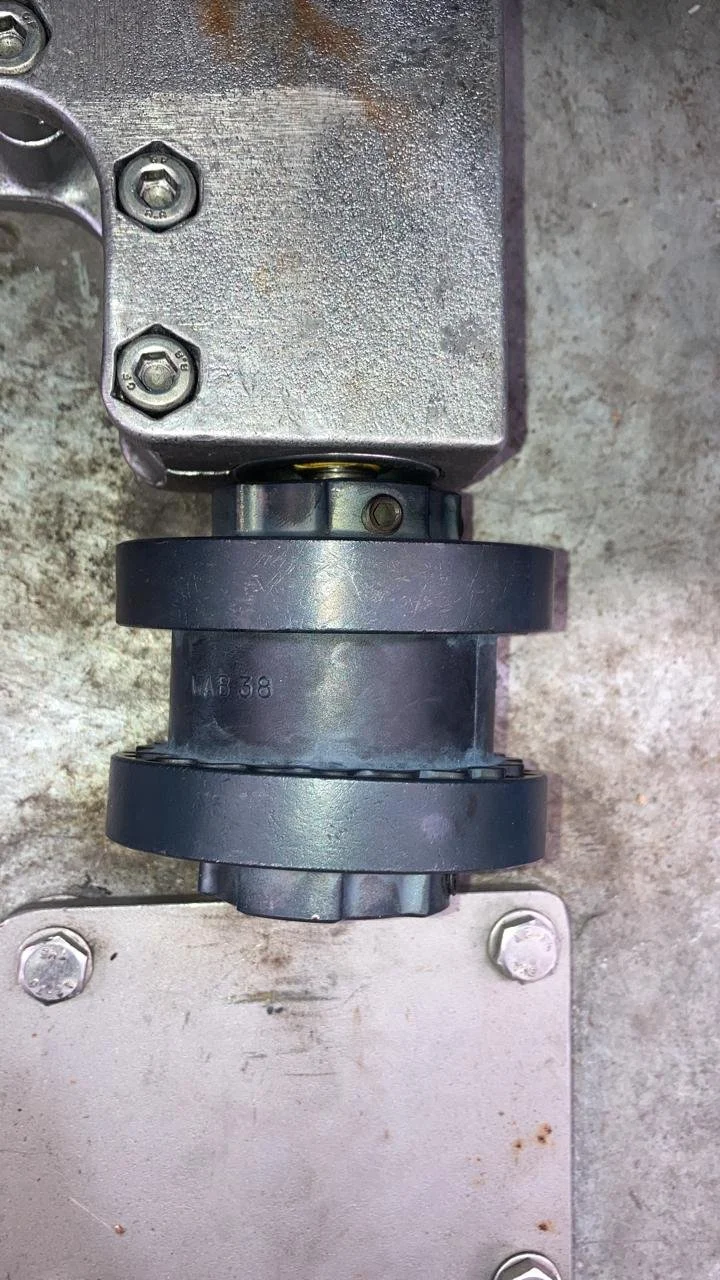 Componentes mecánicos metálicos con tornillos en una superficie de concreto.