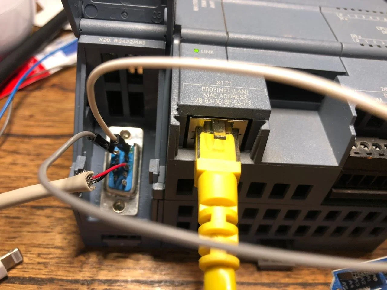 Conexiones y componentes electrónicos en un equipo industrial o informático, incluyendo cables, un enchufe amarillo y un tarjeta de circuito impreso con cables conectados.
