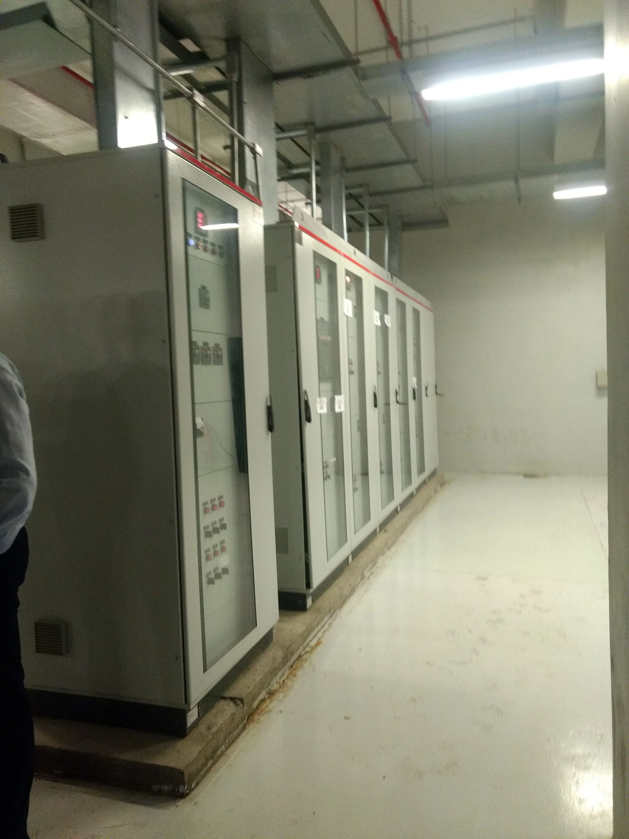 Cajas eléctricas en un pasillo interior, paredes y piso de color claro, iluminación fluorescente en el techo.