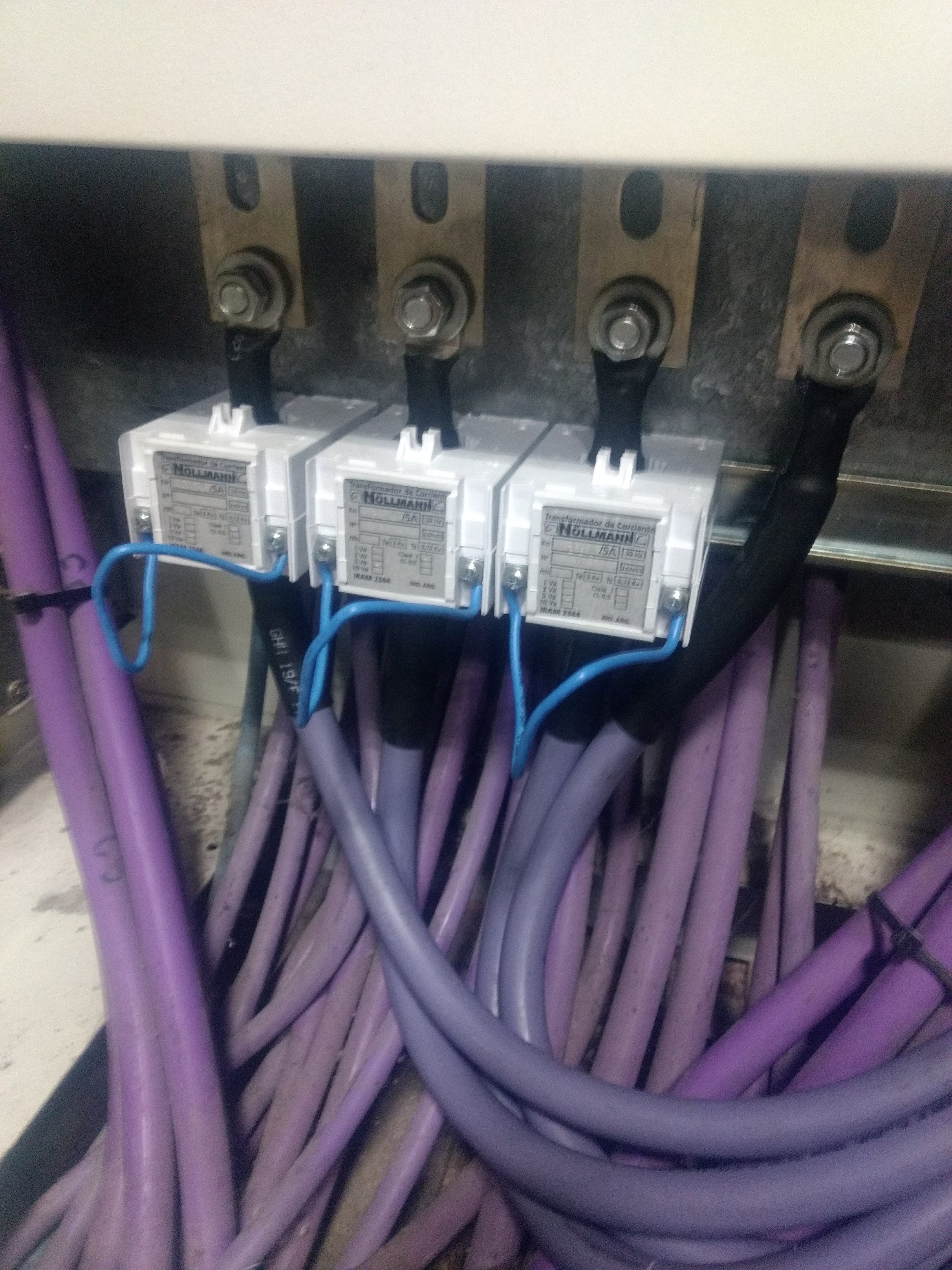 Cables de color morado conectados a un cuadro eléctrico con componentes etiquetados en español.
