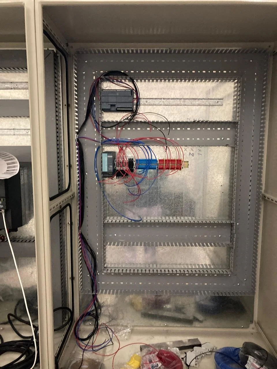 Armario eléctrico en construcción con componentes electrónicos, cables y herramientas en el interior.