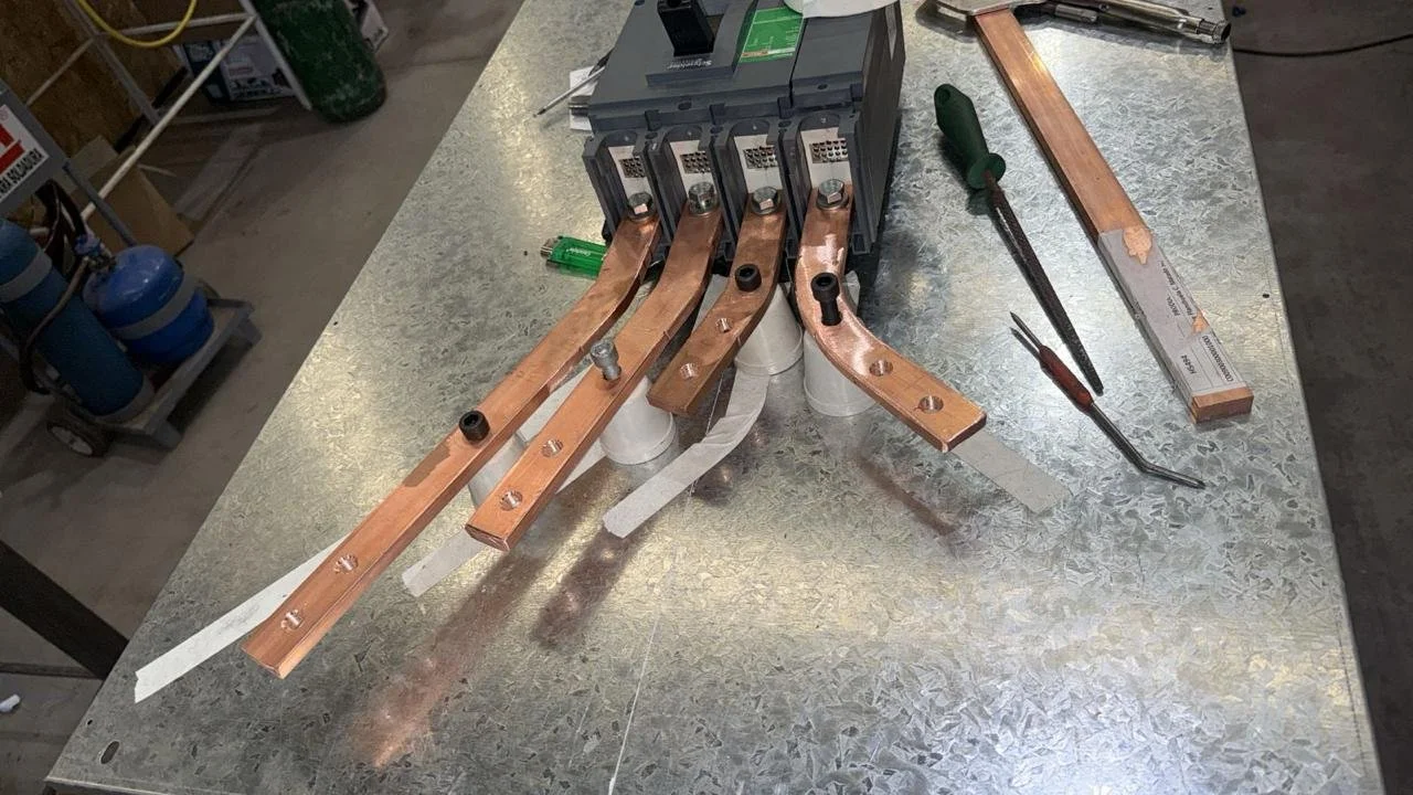 Componentes electrónicos y herramientas en una mesa de trabajo, incluyendo un circuito con cobre, destornilladores y una fuente de alimentación