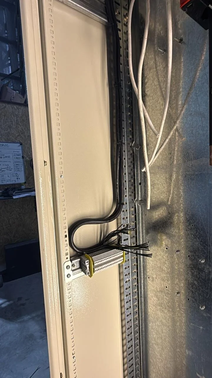 Componentes eléctricos en una caja de distribución, cables negros y blancos, y una regleta con múltiples conexiones.