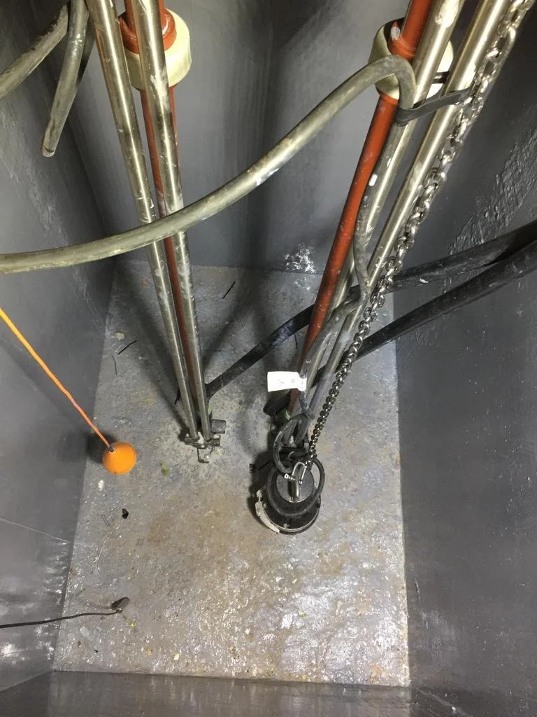 Equipo de fontanería y herramientas en un área de construcción o mantenimiento. Incluye artículos metálicos, un cubo de limpieza, y una cadena.