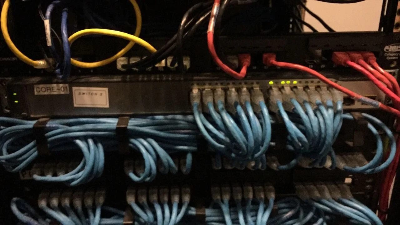 Panel de control de red con cables azul, rojo, negro y amarillo conectados, y luces indicadoras en funcionamiento.
