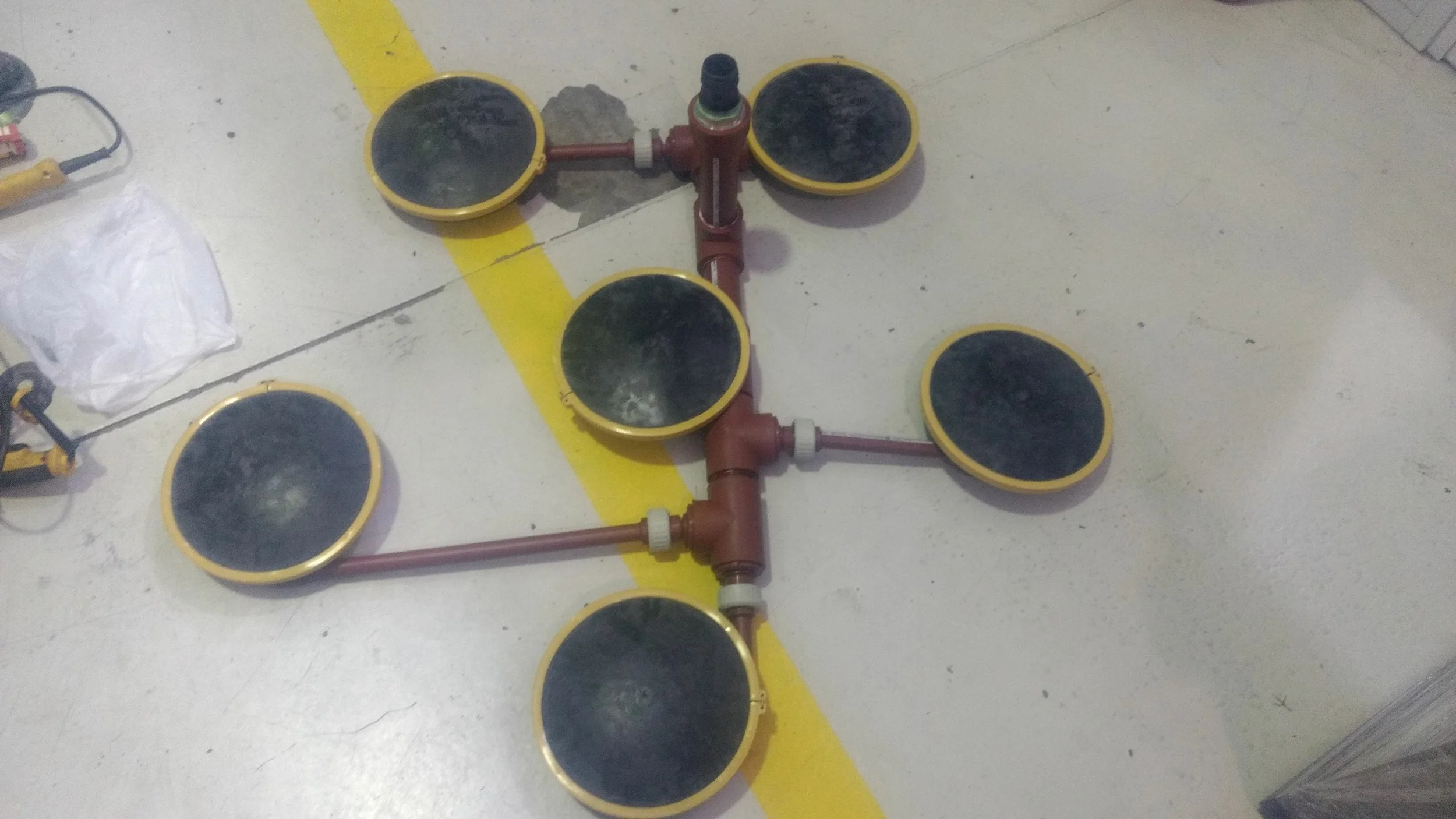 Dispositivo de luces de señalización para seguridad en plantas industriales, con varias luces redondas negras y una estructura de tuberías rojas en el suelo.