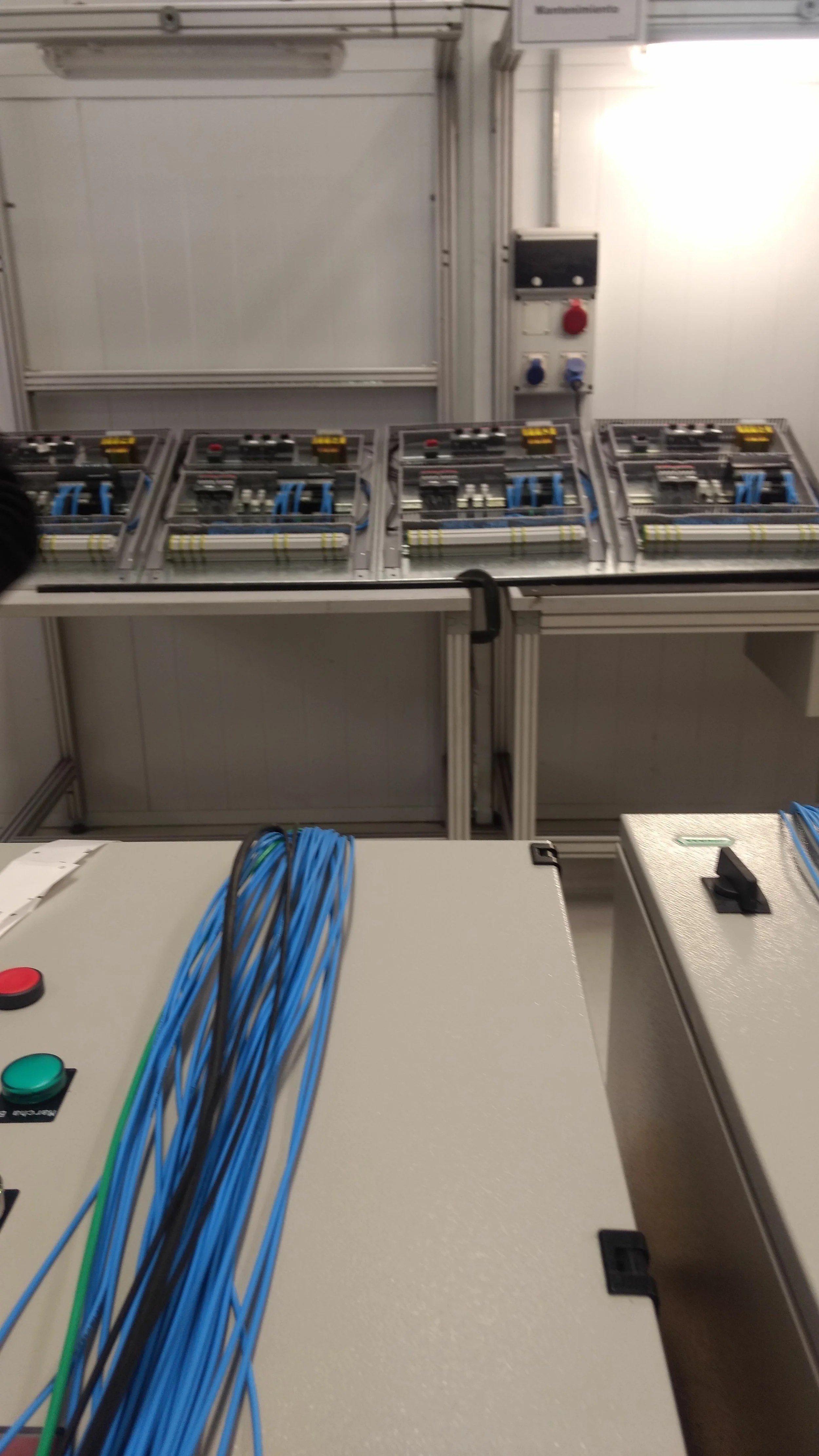 Tableros de control con cables azules y componentes eléctricos en un entorno industrial o de laboratorio.