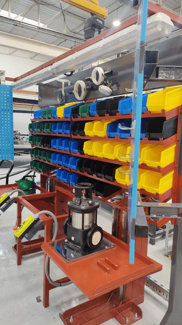 Estantería con bandejas de colores (amarillo, azul, negro y verde) en un entorno industrial con herramientas y maquinaria.