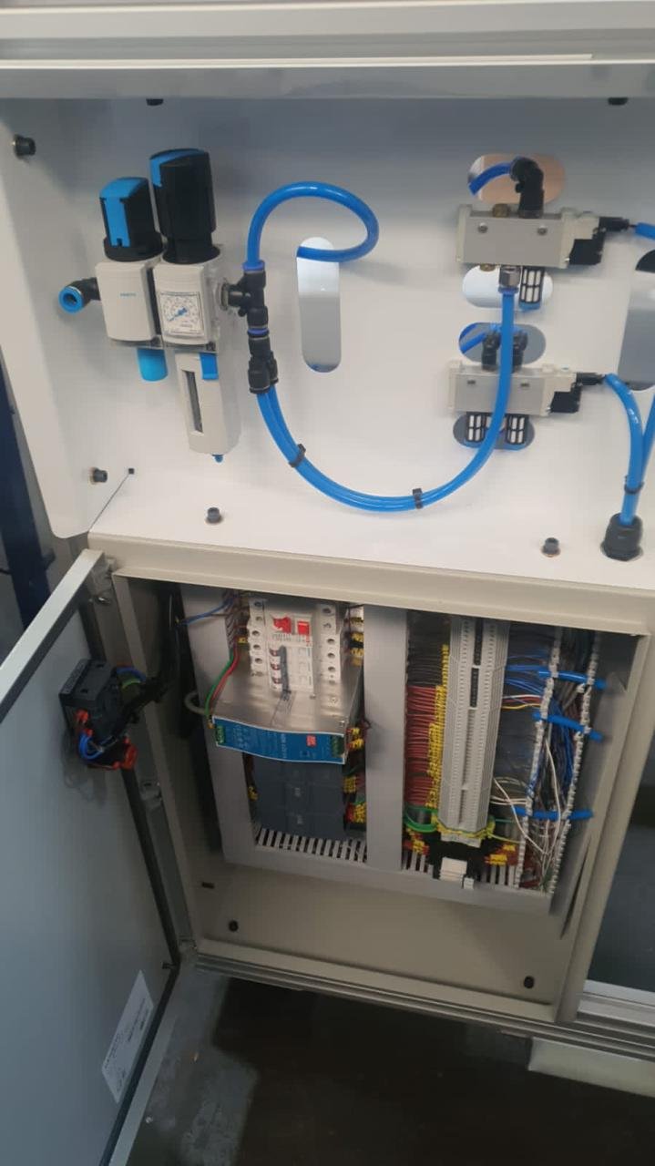 Panel de control con componentes eléctricos y tubería de aire comprimido, incluyendo válvulas, reguladores y conexiones azules.