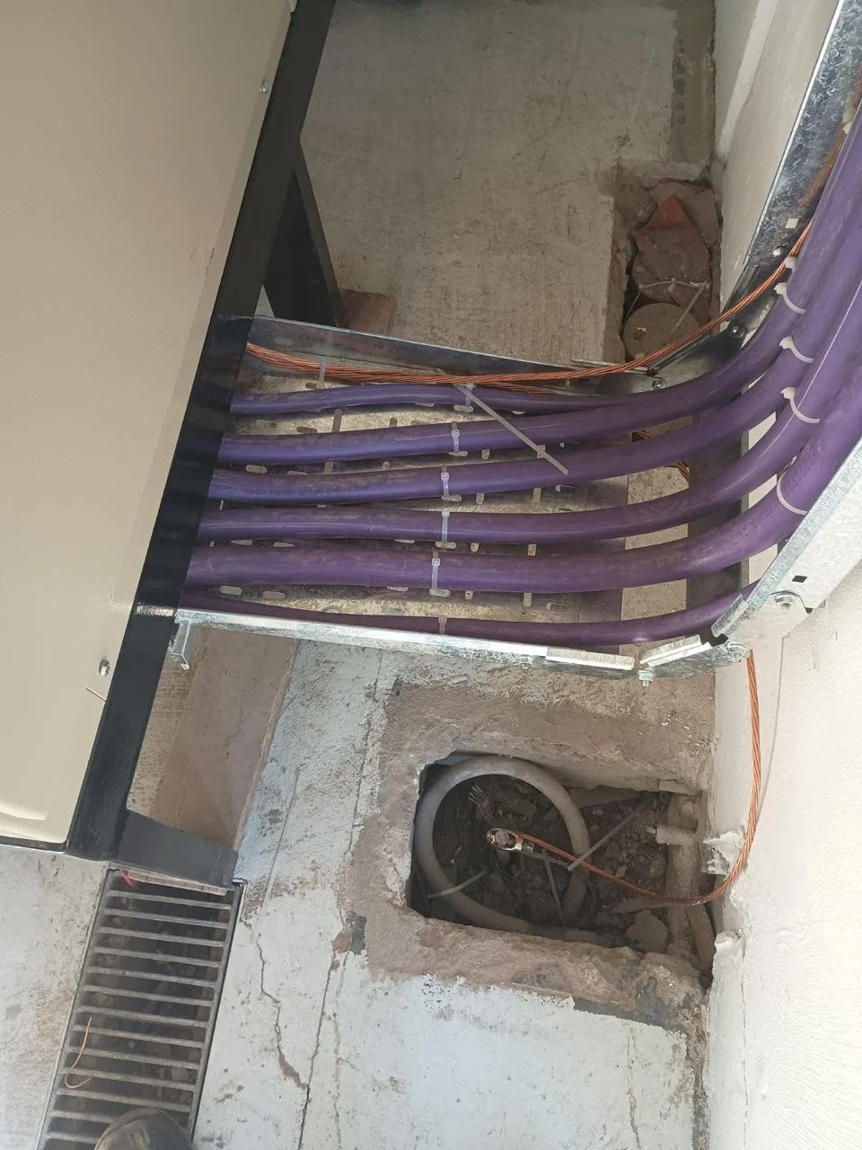 Cableado eléctrico en construcción, con tuberías negras y cables naranjas en un sitio en obra