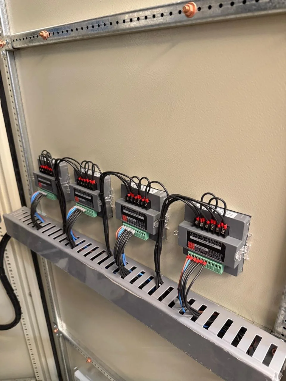 Cuatro controladores electrónicos montados en una bandeja metálica con cables conectados.