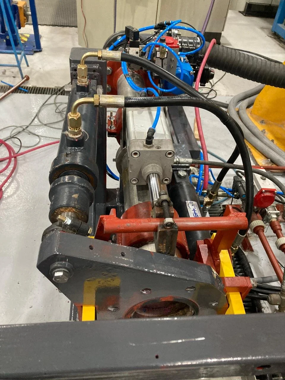 Una máquina industrial con tuberías, mangueras, y componentes metálicos en un taller.