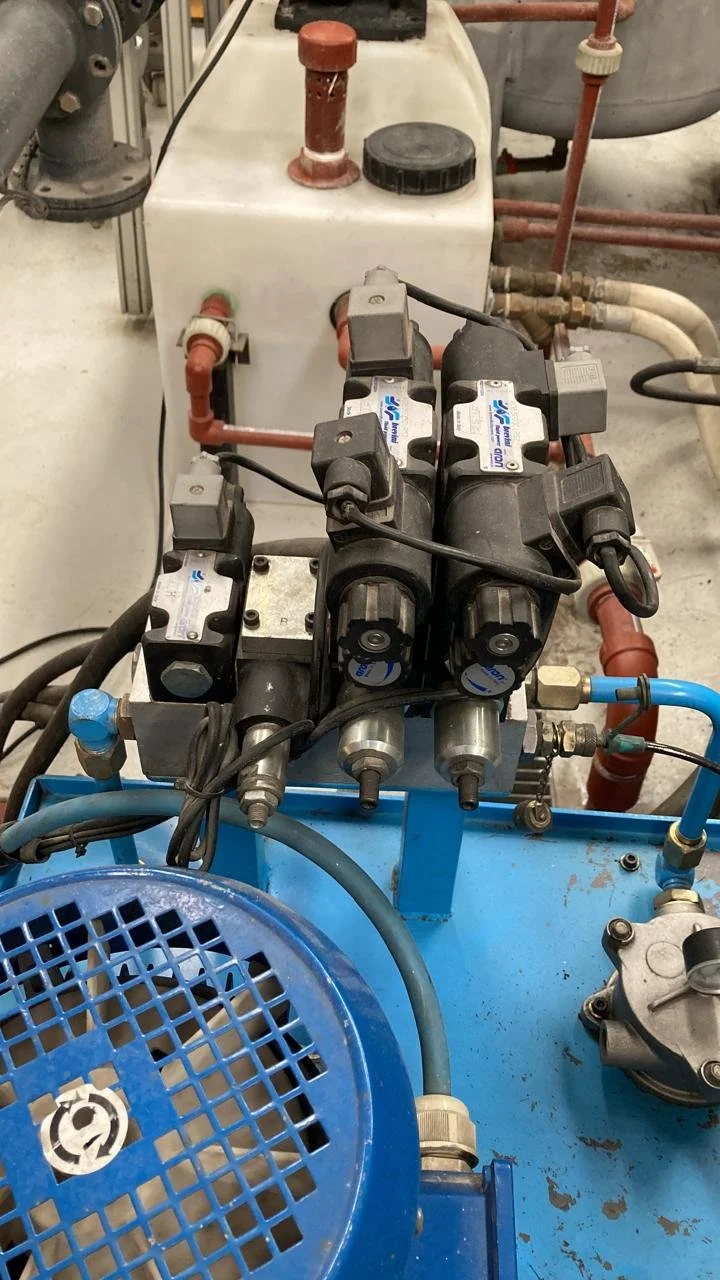 Componentes mecánicos y eléctricos en un equipo industrial con tuberías, válvulas y bombas, en un entorno de planta.