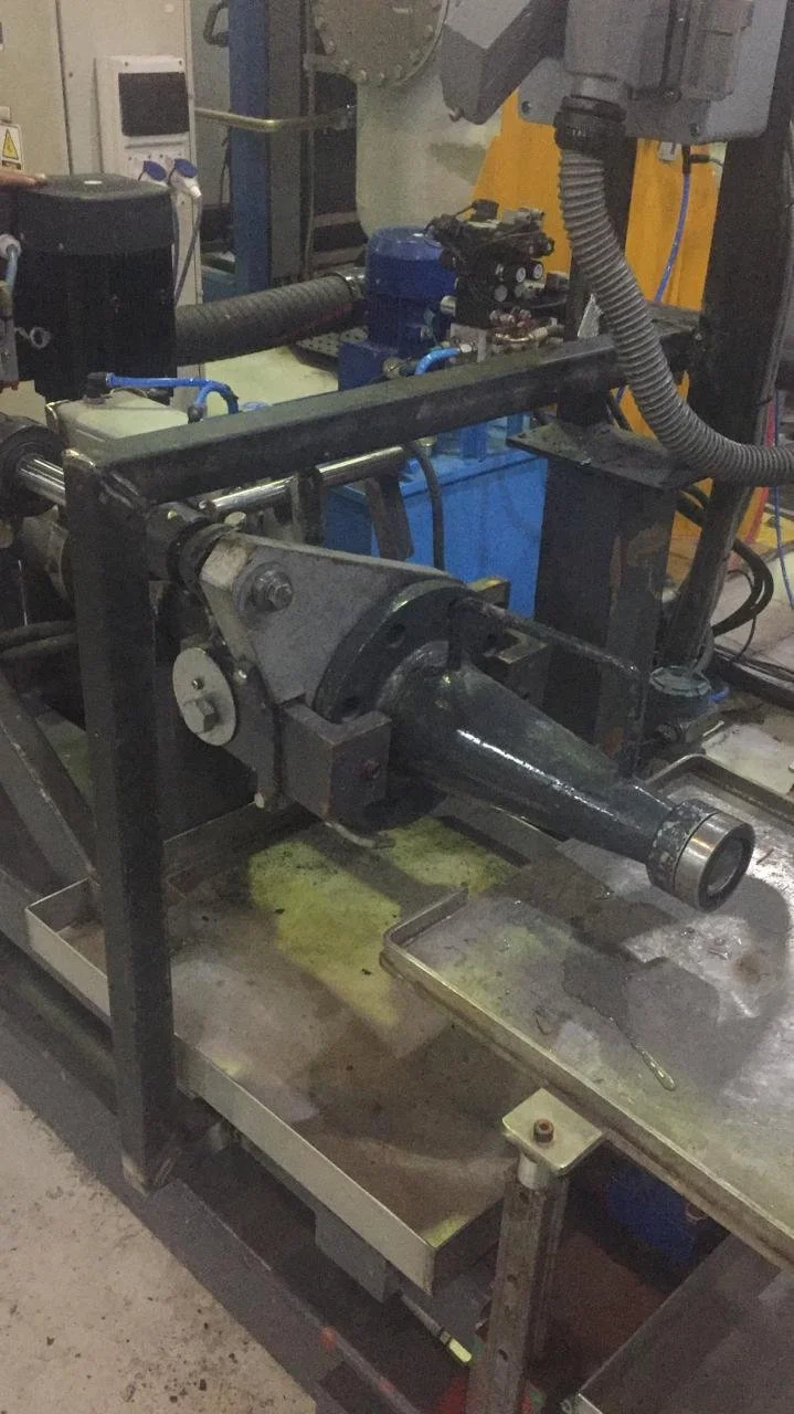 Imagen de un equipo industrial con un tubo y componentes mecánicos en un entorno de fábrica.