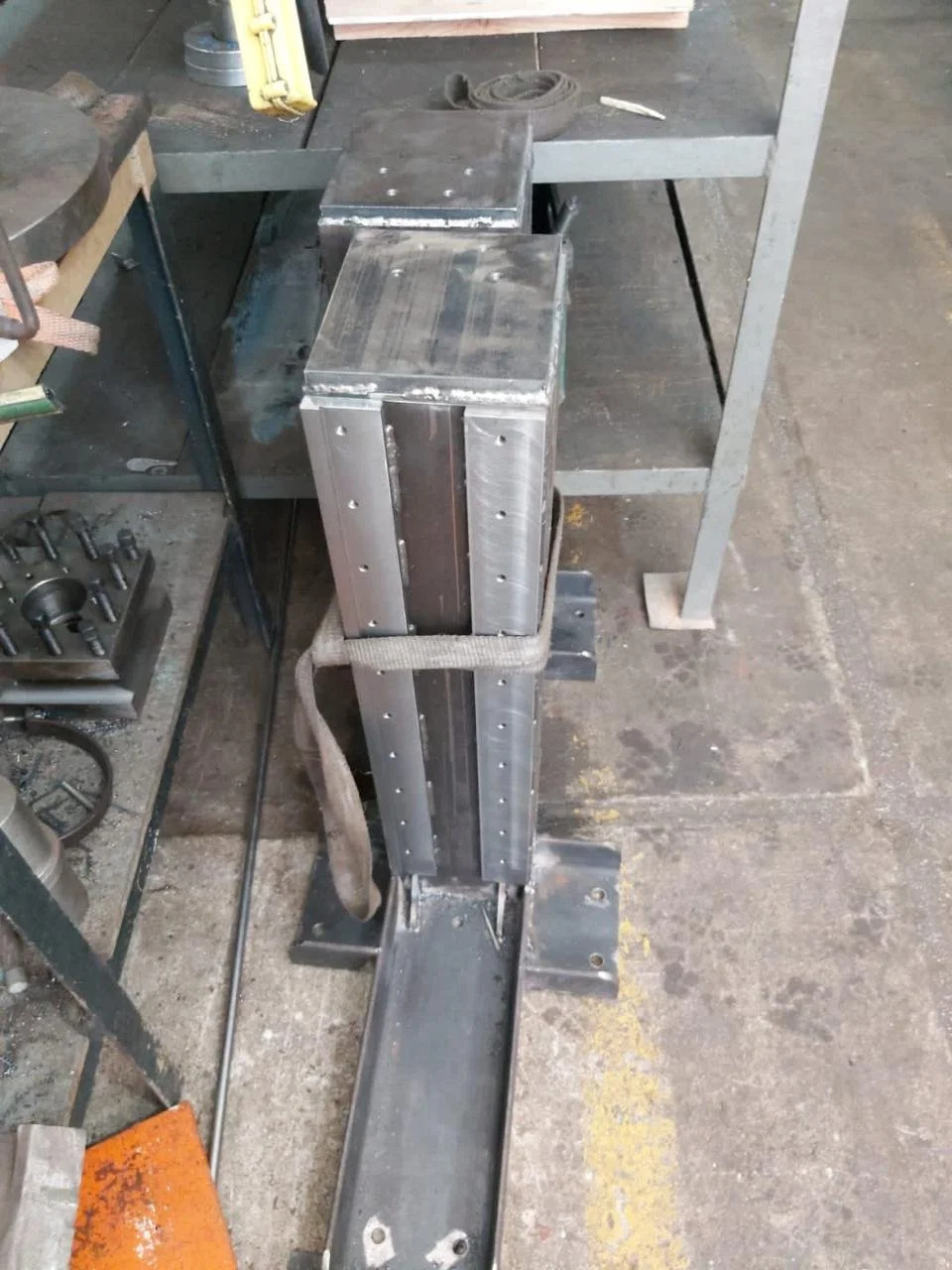 Componentes metálicos en un taller de fabricación, con una mesa de trabajo y herramientas alrededor.