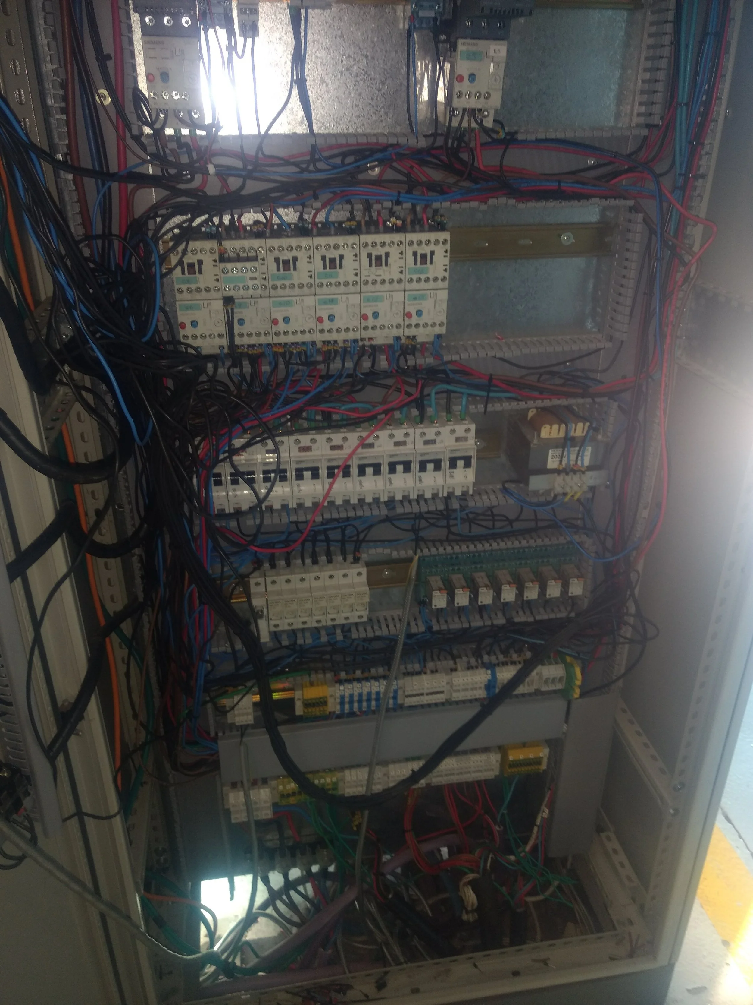 Cuadro eléctrico con cables y componentes eléctricos en su interior.
