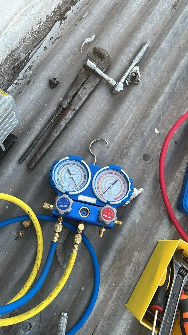 Compresor de aire con manómetro y mangueras de color azul y amarillo, herramientas en una superficie de trabajo