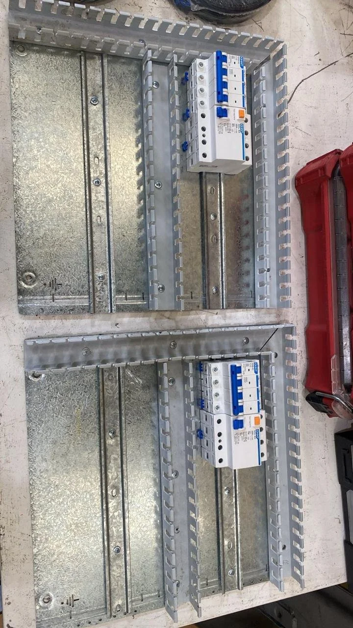 Dos cajas de interruptores automáticos montadas en una base de metal, con una caja de superficie y un marco para instalar.