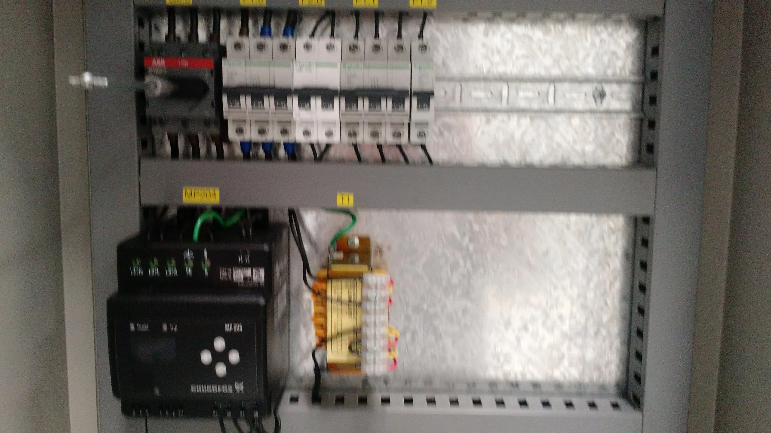 Un tablero de eléctrica con componentes y cables, incluyendo contactos, fusibles y un relé, dentro de una caja metálica de distribución.