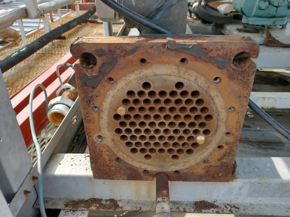 Foto de un equipo industrial rustico con múltiples tubos y componentes metálicos en un entorno de fábrica o taller, con signo evidente de oxidación y uso prolongado.