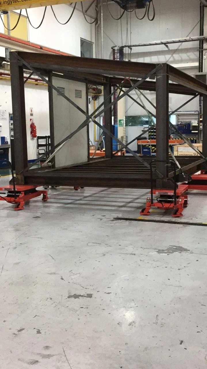 Estructura metálica en una fábrica, en proceso de ensamblaje, con equipo y herramientas alrededor.