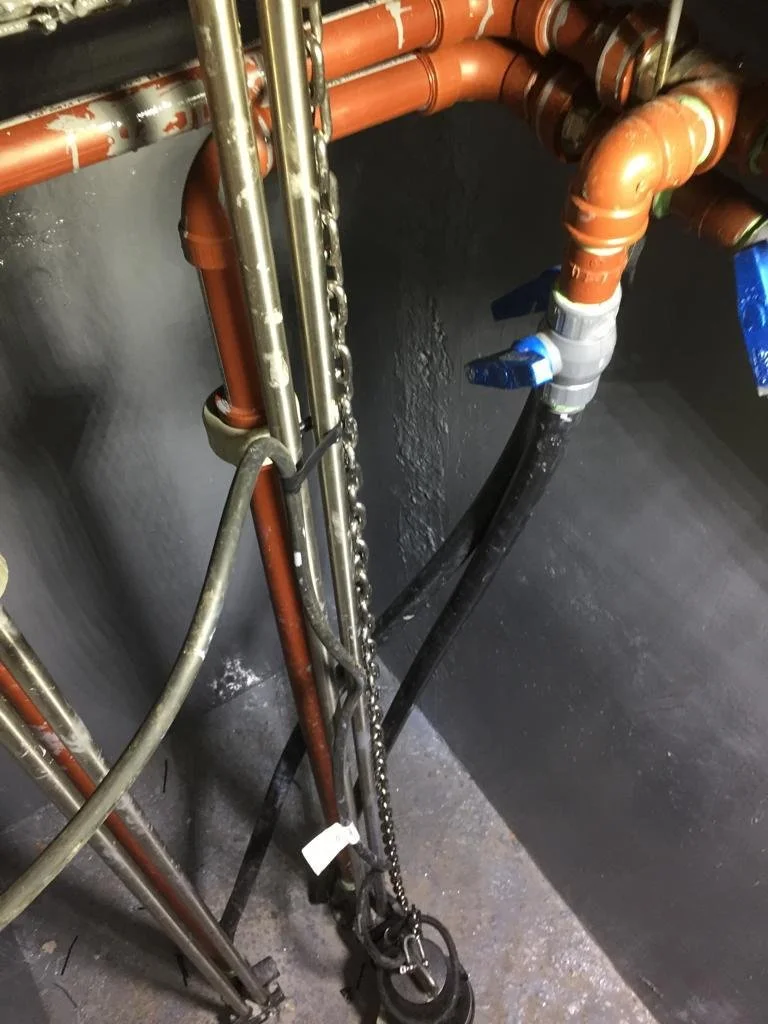 Tuberías de cobre y acero, con válvula azul, en un espacio de tuberías y cables.