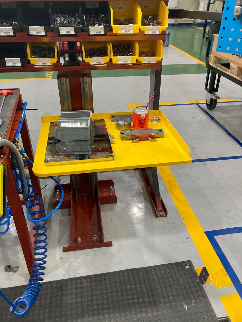 Mesa de trabajo de taller con herramientas y piezas metálicas en un entorno industrial.