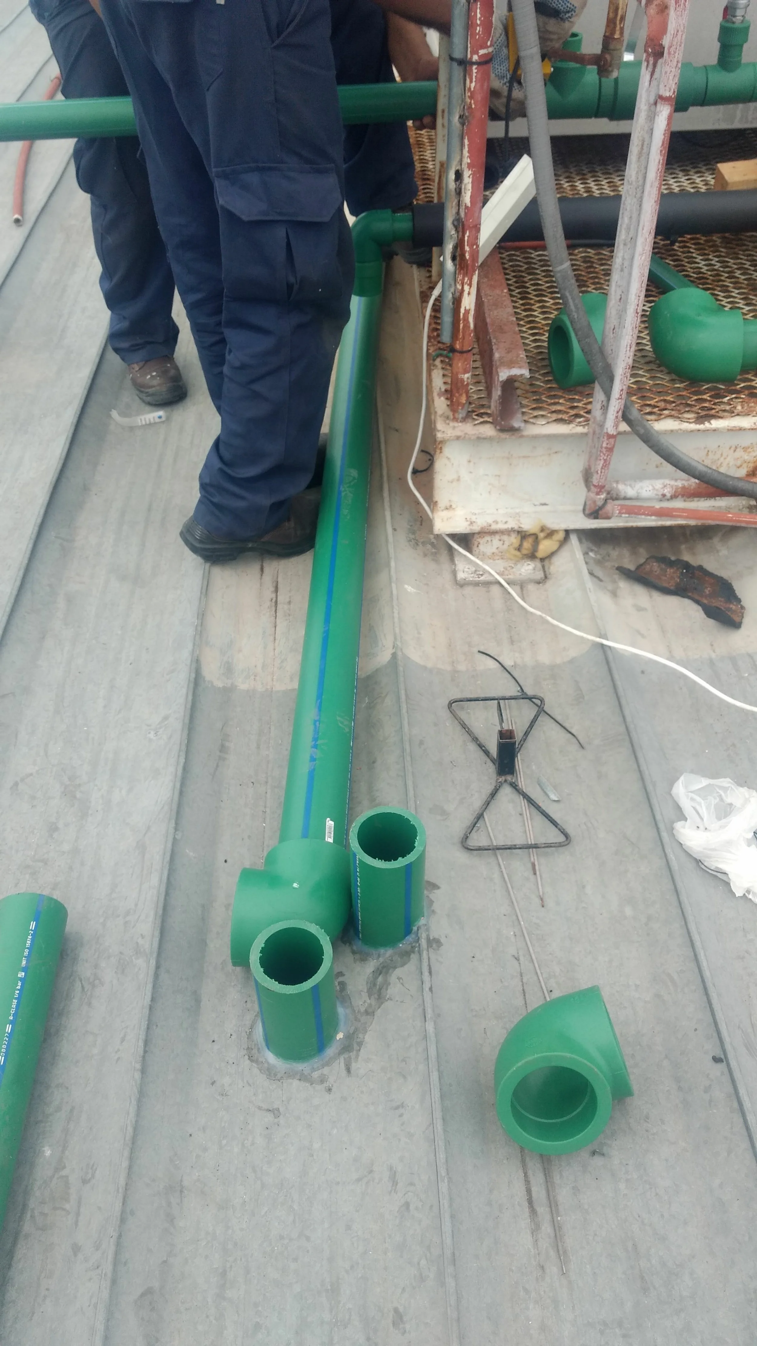 Trabajadores montando tubería de plástico verde en construcción.