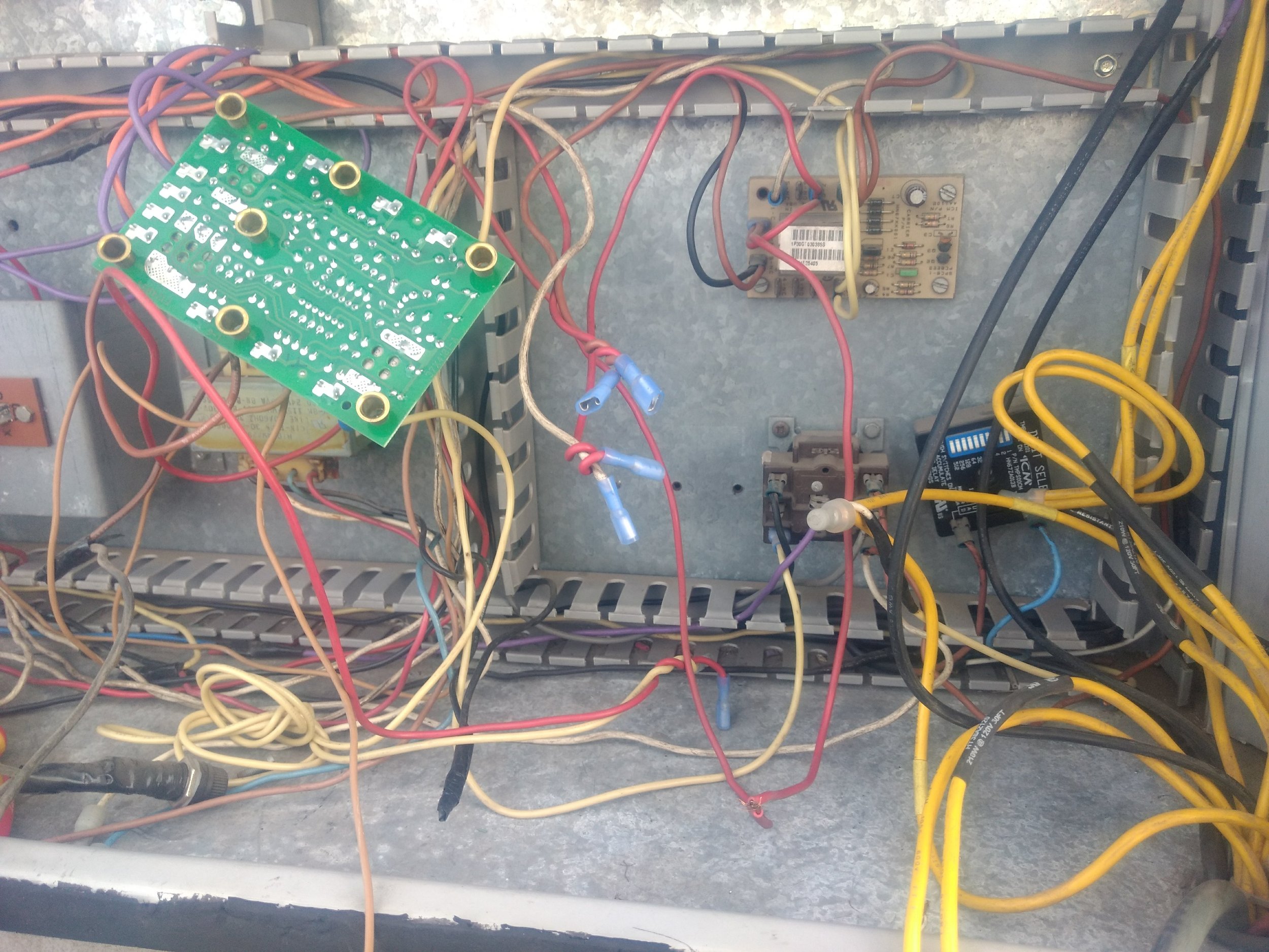 Caja de conexiones eléctricas con cables de diferentes colores y una placa de circuito.