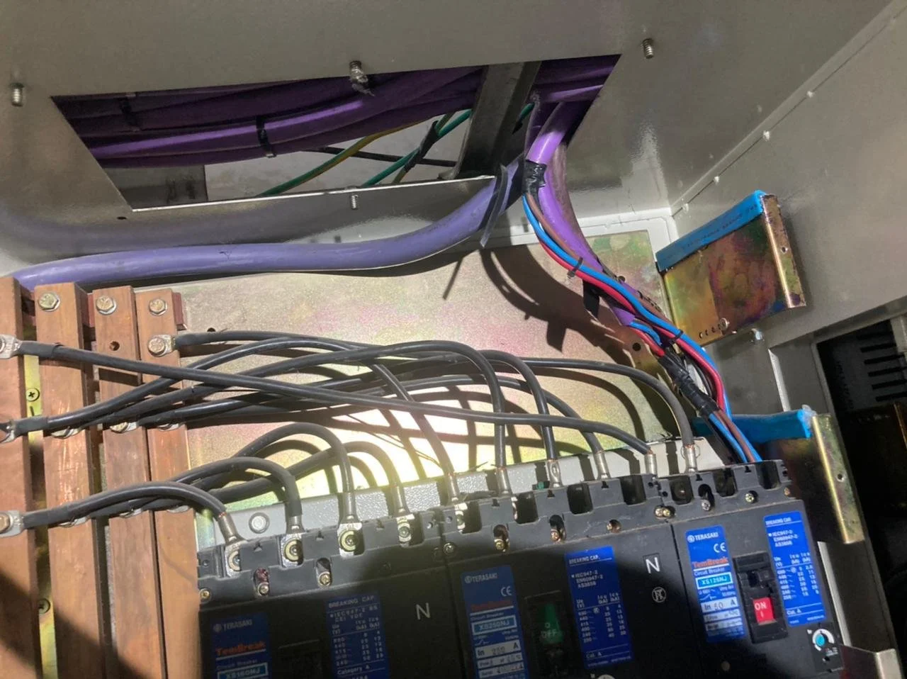 Interior de un panel eléctrico con cables, disyuntores y componentes metálicos.