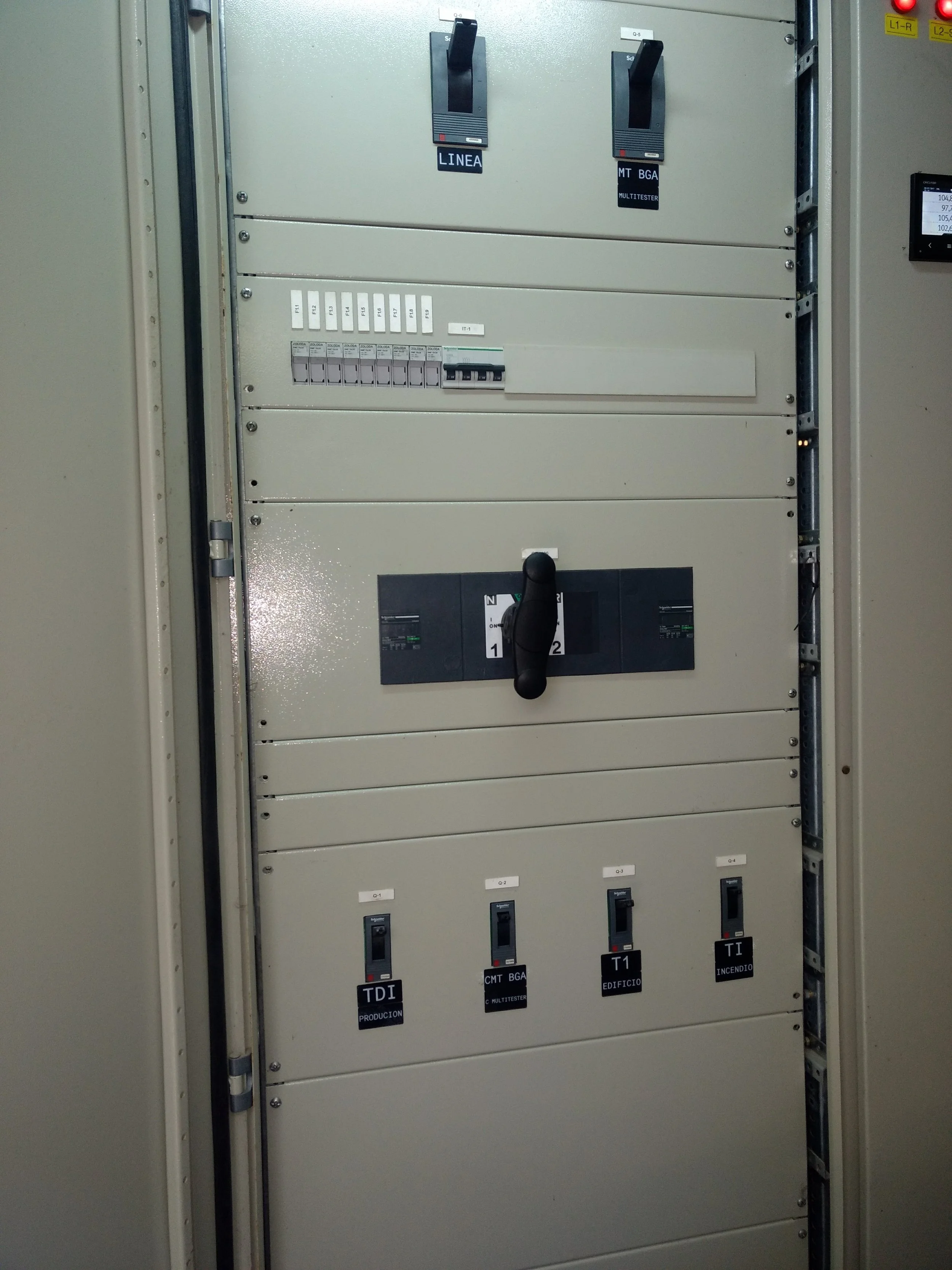 Un panel de control eléctrico con interruptores y etiquetas en español, incluyendo etiquetas como 'TDI PRODUCCION', 'CMT BGA MULTISTER', 'T1 EDIFICIO', y 'T1 INCENDIO'.