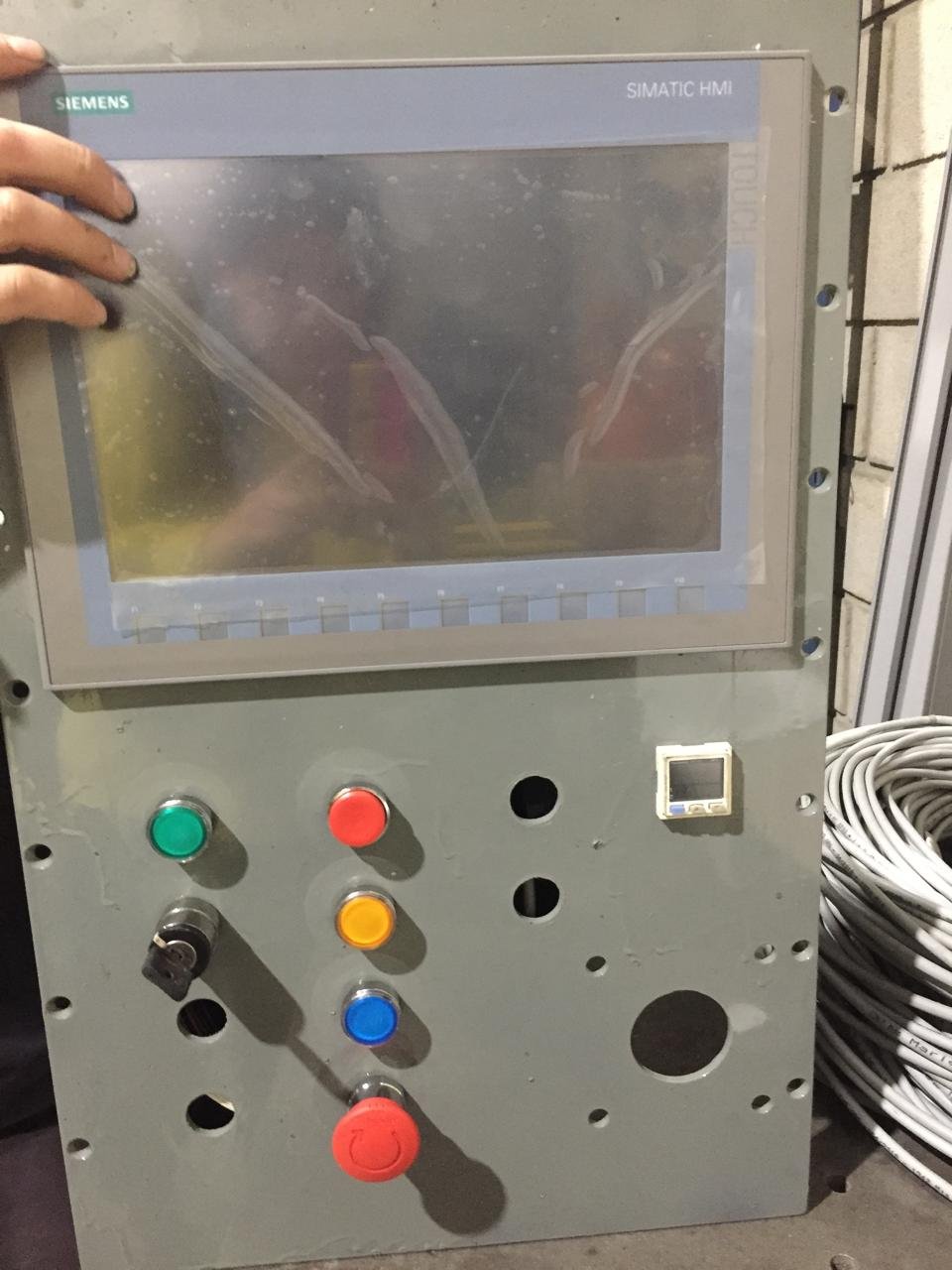 Panel de control industrial Siemens Simatic HMI con botones de diferentes colores y pantalla táctil.