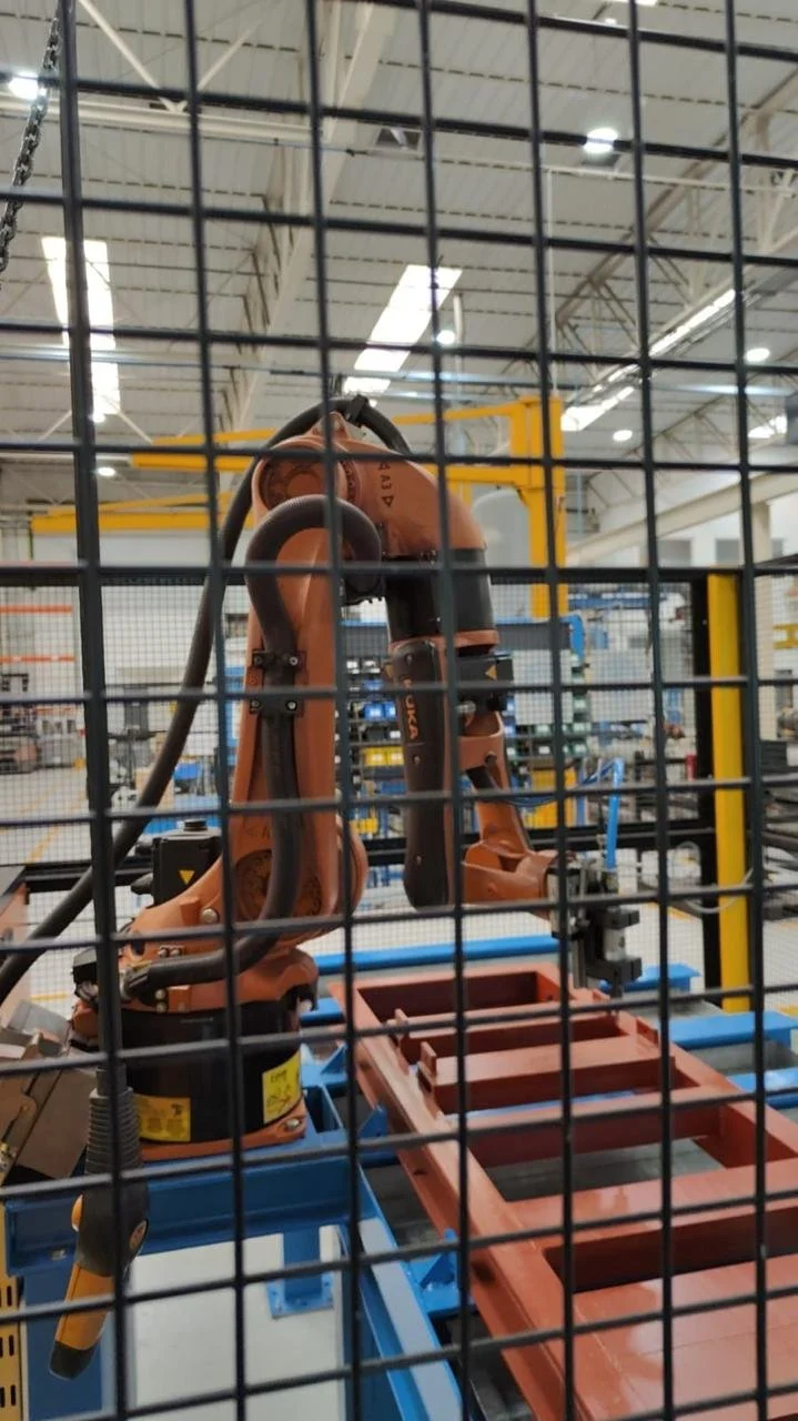 robot industrial en una fábrica, visto a través de una reja de protección