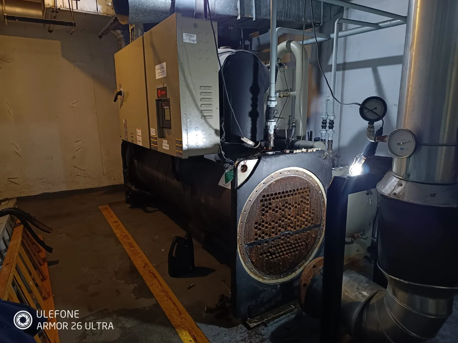 Equipo de maquinaria industrial en una sala de instalaciones, con tuberías y medidores de presión.